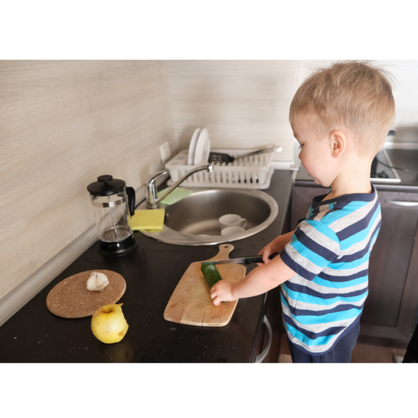 Boy chopping Zuchinni in a kitchen in a Montessori Homeschool