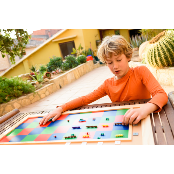 Boy sorting colored magnets on a checkered board in a Montessori Homeschool